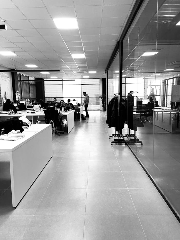 heros-img Black and white of anonymous employees working together in modern office with glass walls